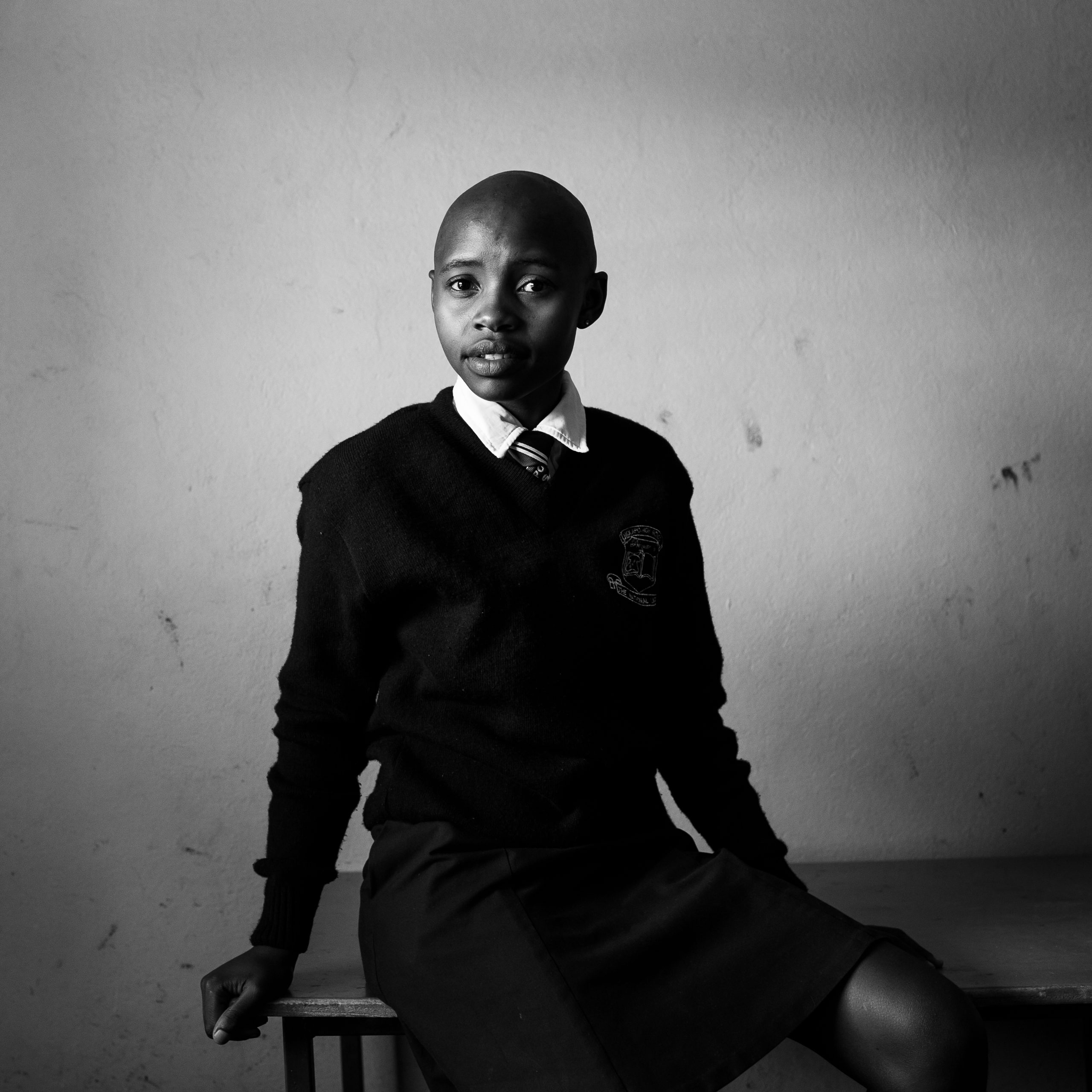 A black and white photo of a school student, wearing their class uniform.